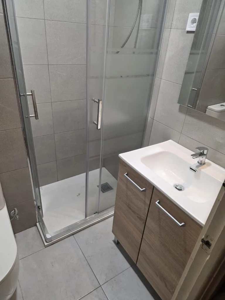 Baño con plato de ducha, mampara de cristal y mueble de lavabo