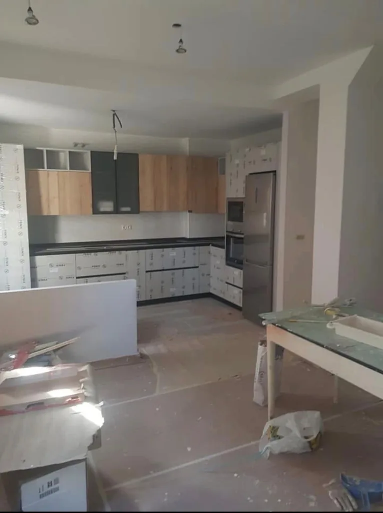 Cocina reformada con muebles en dos tonos, encimera oscura y electrodomésticos integrados